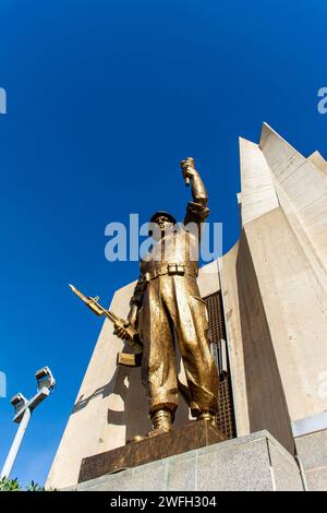 Vista dall'angolo basso di una statua di un soldato con una torcia e una pistola nel monumento Maqam Echahid contro un cielo blu. Foto Stock