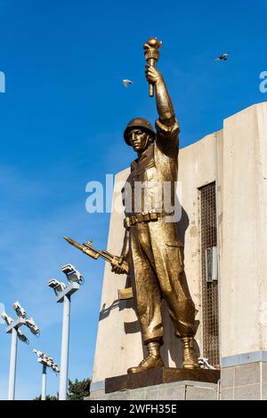 Vista dall'angolo basso di una statua di un soldato con una torcia e una pistola nel monumento Maqam Echahid contro un cielo blu. Foto Stock