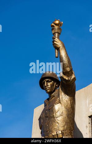 Vista dall'angolo basso di una statua di un soldato con una torcia e una pistola nel monumento Maqam Echahid contro un cielo blu. Foto Stock