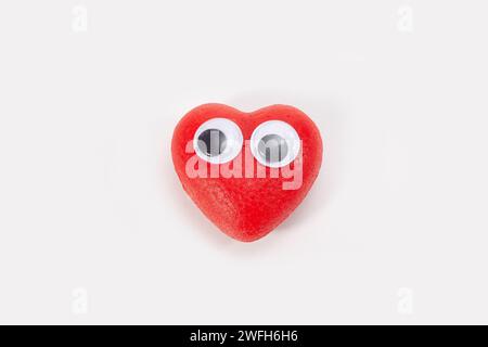 piccolo cuore rosso con occhi isolati su sfondo bianco Foto Stock