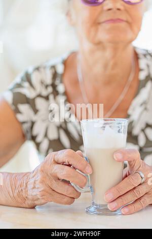 Foto ritagliata di una donna anziana che tiene una tazza di caffè all'aperto Foto Stock