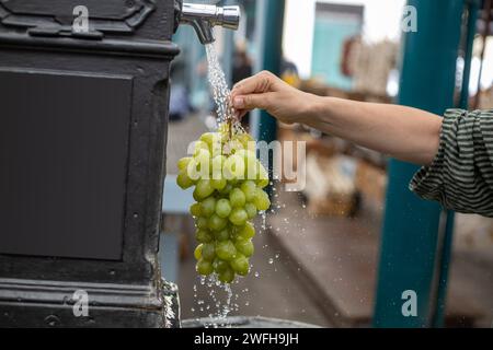 risciacquare un mazzo di uva bianca con acqua al mercato Foto Stock