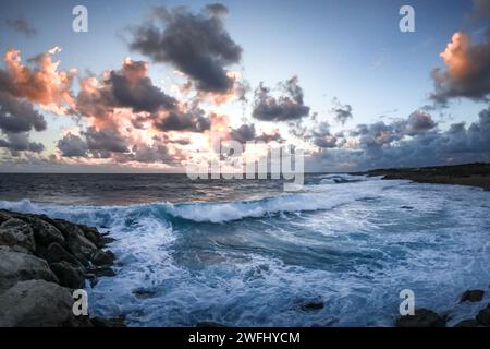 Splendido tramonto sul mare mediterraneo tempestoso, Paphos, Cipro. Spiaggia rocciosa, inverno, nuvole di tempesta nel cielo. Foto Stock