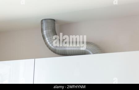 Tubo di ventilazione ondulato in alluminio espandibile in cucina che collega una cappa da cucina e un albero dell'aria di ventilazione. Foto Stock