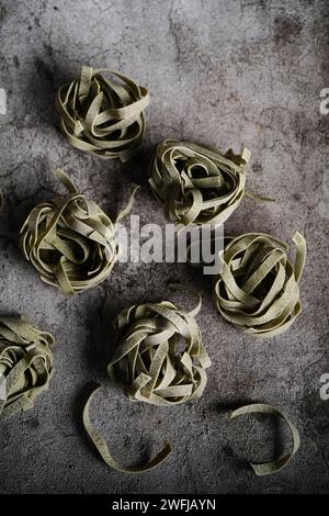 Fettuccine di spinaci crudi secchi su fondo rustico, messa a fuoco selettiva Foto Stock