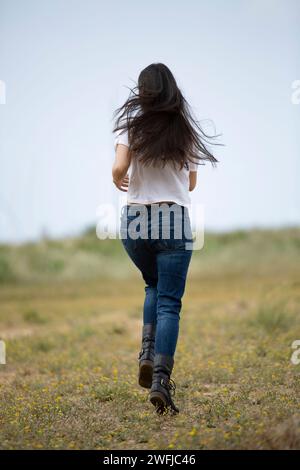 Vista posteriore di una giovane donna che corre all'aperto Foto Stock
