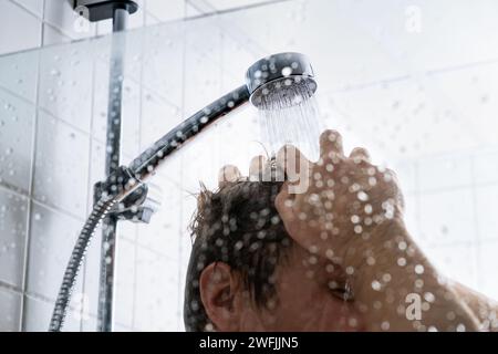 Lavare i capelli con lo shampoo. Uomo sotto la doccia. Acqua fredda o calda. Balsamo, gel o schiuma. Concetto di taglio, perdita, forfora o danno. Cuoio capelluto prurito secco. Foto Stock