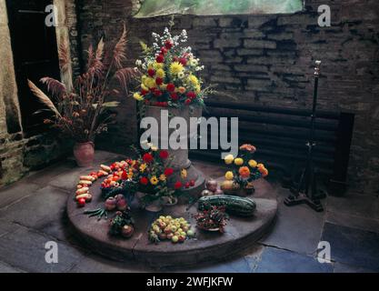 Fonte normanna nella chiesa di St Torney, North Hill, Cornovaglia, Inghilterra, Regno Unito, decorato per il Festival del raccolto nell'ottobre 1990: fiori, frutta e verdura Foto Stock