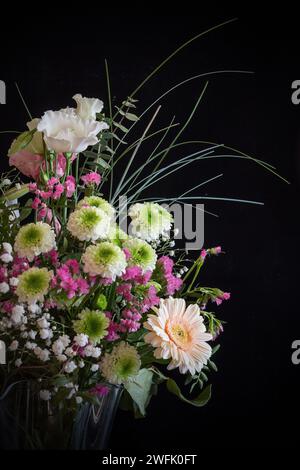 Natura morta di un bouquet di fiori in tonalità scure e moody con sfondo nero Foto Stock