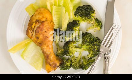 Ricetta di cosce di pollo al forno e broccoli. Pasto su un piatto bianco, piatto piatto Foto Stock