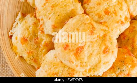 Biscotti al formaggio con burro e aglio condimento primo piano su un piatto di legno, vista dall'alto, mani di donna Foto Stock