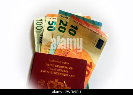 Varie denominazioni di banconote in euro e una copertina del passaporto rosso britannico. Studio impostato su sfondo bianco Foto Stock