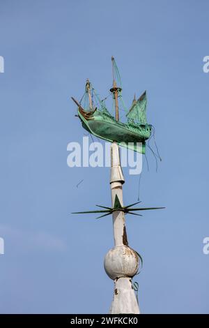 Un'antichissima paletta di galeone adagiata in cima a una casa storica nella Vecchia Portsmouth. Adagiato su un lato del porto blu illuminato dal sole. Foto Stock