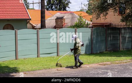 Johannesburg, Sudafrica - un lavoratore migrante non identificato fa lavori manuali di giardinaggio per guadagnarsi da vivere Foto Stock