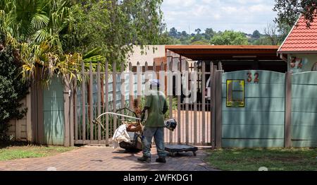 Johannesburg, Sudafrica - un lavoratore migrante non identificato fa lavori manuali di giardinaggio per guadagnarsi da vivere Foto Stock