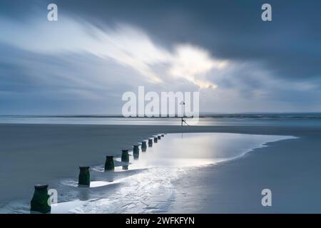 Un cielo in rapido movimento e lunare corre attraverso la splendida spiaggia di West Wittering e guardando verso l'Isola di Wight Foto Stock