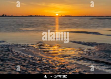 Un altro incredibile tramonto dalla spiaggia di West Wittering che rivela sabbia scolpita e guarda dall'altra parte dell'acqua verso Hayling Island Foto Stock