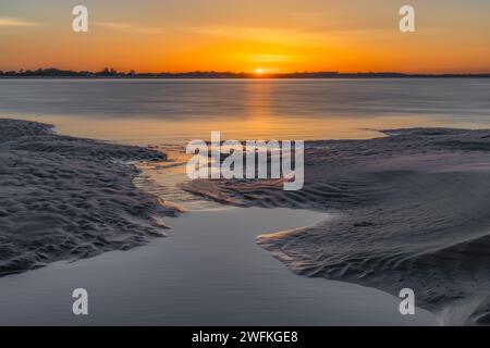 Un altro incredibile tramonto dalla spiaggia di West Wittering che rivela sabbia scolpita e guarda dall'altra parte dell'acqua verso Hayling Island Foto Stock