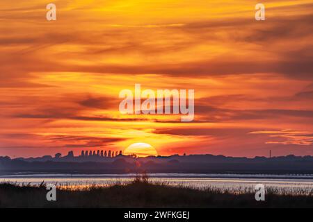 Un cielo molto tranquillo con il sole che tramonta dietro gli alberi nel bellissimo porto di Chichester, preso dalla costa di Itchenor Foto Stock