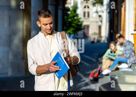 Studente universitario in piedi con un libro che ha una pausa tra le lezioni. Foto Stock
