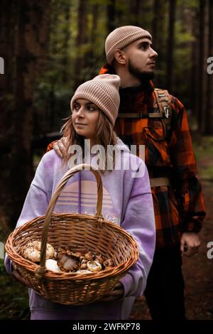 giovane coppia di turisti con un cesto che raccoglie funghi nella foresta Foto Stock