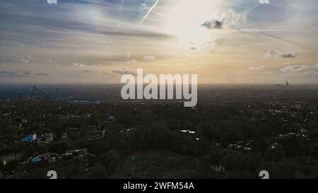 Vista aerea di un paesaggio urbano al crepuscolo con nuvole sparse e un bagliore al tramonto. Foto Stock