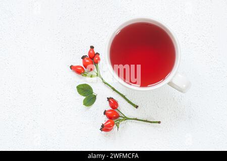 Tazza di Rosehip erbe tè piante medicinali con frutti rosehip su tavola bianca. Tè invernale dogrose Foto Stock