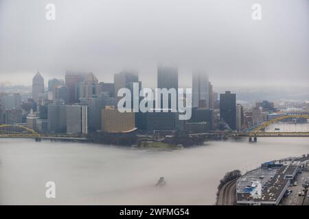 Una towboat naviga attraverso la nebbia del fiume Ohio a Pittsburgh, 25 gennaio 2024. Il U.S. Army Corps of Engineers Pittsburgh District gestisce 23 chiuse navigabili e dighe sui fiumi Allegheny, Monongahela e Ohio tutto l'anno, indipendentemente dalle condizioni meteorologiche, anche in condizioni di nebbia che limitano la visibilità. Molti equipaggi di barche a rimorchio continuano a lavorare sui fiumi anche nella nebbia, talvolta mettendo in scena le loro chiatte lungo varie parti lungo i corsi d'acqua di Pittsburgh mentre aspettano che la nebbia si sollevi. Indipendentemente dal tempo, le chiuse e le dighe del distretto di Pittsburgh rimangono aperte al traffico, pronte per ogni evenienza Foto Stock