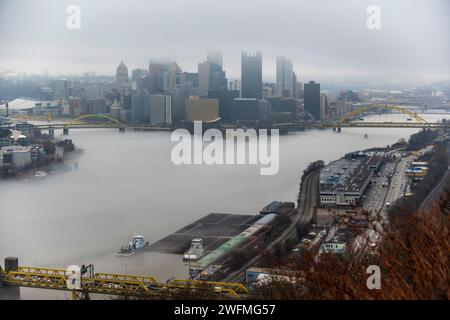 Towboats organizza chiatte in condizioni di nebbia sul fiume Ohio a Pittsburgh, 25 gennaio 2024. Il U.S. Army Corps of Engineers Pittsburgh District gestisce 23 chiuse navigabili e dighe sui fiumi Allegheny, Monongahela e Ohio tutto l'anno, indipendentemente dalle condizioni meteorologiche, anche in condizioni di nebbia che limitano la visibilità. Molti equipaggi di barche a rimorchio continuano a lavorare sui fiumi anche nella nebbia, talvolta mettendo in scena le loro chiatte lungo varie parti lungo i corsi d'acqua di Pittsburgh mentre aspettano che la nebbia si sollevi. Indipendentemente dal tempo, le chiuse e le dighe del distretto di Pittsburgh rimangono aperte al traffico, re Foto Stock