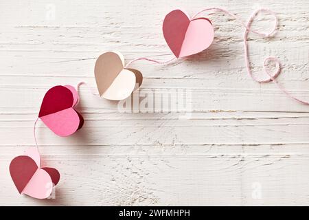 decorazione in carta a forma di cuore su sfondo di legno bianco, vista dall'alto Foto Stock
