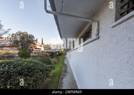 Corridoio esterno perimetrale di un edificio residenziale con aree comuni paesaggistiche con erba e siepi ben curate Foto Stock