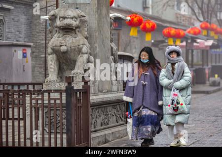 QINGZHOU, CINA - 31 GENNAIO 2024 - i turisti giocano nel luogo panoramico dell'antica città di Qingzhou con spessi abiti imbottiti di cotone nello Shandong della Cina orientale Foto Stock