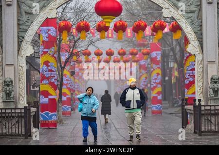 QINGZHOU, CINA - 31 GENNAIO 2024 - i turisti giocano nel luogo panoramico dell'antica città di Qingzhou con spessi abiti imbottiti di cotone nello Shandong della Cina orientale Foto Stock