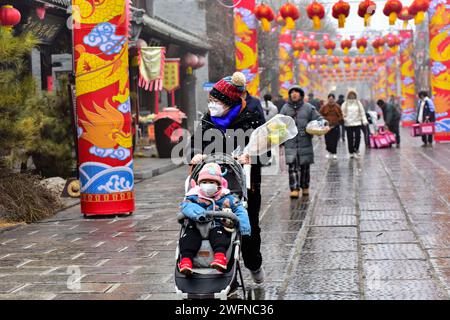 QINGZHOU, CINA - 31 GENNAIO 2024 - i turisti giocano nel luogo panoramico dell'antica città di Qingzhou con spessi abiti imbottiti di cotone nello Shandong della Cina orientale Foto Stock