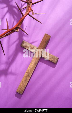 Croce di legno e corona di spine su sfondo viola Foto Stock