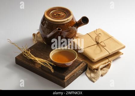 Un podio di legno con una ciotola di medicina e Dang Shen messo su, esposto con una pentola di terra e alcuni pacchetti di medicine. Terapia erboristica cinese Foto Stock