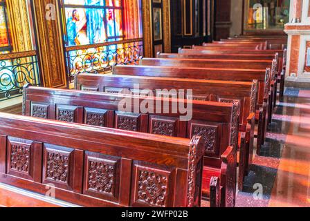 Panchine vuote in legno di una chiesa cristiana. Alterazione sfocata sullo sfondo. Messa a fuoco selettiva. Concetto di servizio religioso o chiese vuote. Righe Foto Stock