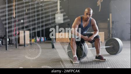 Immagine dell'elaborazione dei dati sull'interfaccia dell'uomo birazziale seduto su pesi da barcampanello in palestra Foto Stock