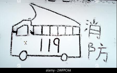 ZAOZHUANG, CINA - 1° FEBBRAIO 2024 - Un vigile del fuoco disegna un modello di camion dei pompieri con il piede nella neve in un campo di addestramento della brigata dei pompieri e dei soccorritori Foto Stock