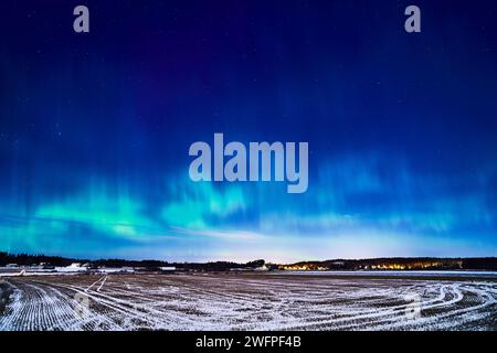 Una splendida esposizione dell'aurora boreale che illumina il cielo e un campo pittoresco Foto Stock