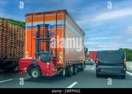 Carrelli elevatori a forche montati su autocarri, noti anche come carrelli elevatori a forche con ruote piggyback che viaggiano in autostrada durante il traffico intenso Foto Stock