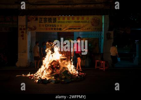 Georgetown, Penang, Malesia - 29 gennaio 2023: La gente del posto sta bruciando offerte di carta dorata in strada per il capodanno cinese Foto Stock
