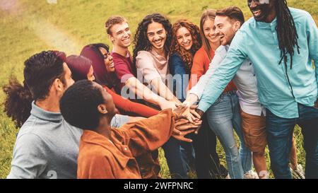 Gli amici entusiasti si uniscono alle mani all'aperto, mostrando lo spirito di squadra e l'unità in mezzo alla natura. Foto Stock