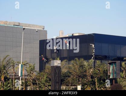 Cairo, Egitto, 23 gennaio 2024: Manutenzione e pulizia dell'esterno di un edificio, pulizia dei vetri da parte dei lavoratori su fili per fornire il servizio di pulizia da Foto Stock