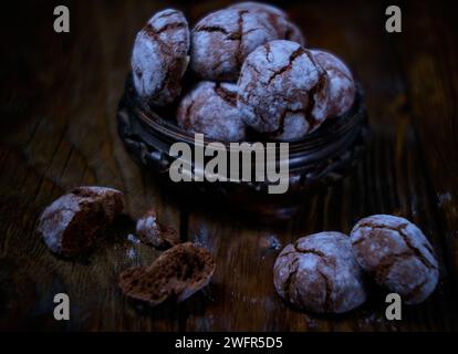 Biscotti croccanti al cioccolato con zucchero a velo in un vaso di legno. Biscotti al cioccolato incrinati su legno. tabella. Foto Stock