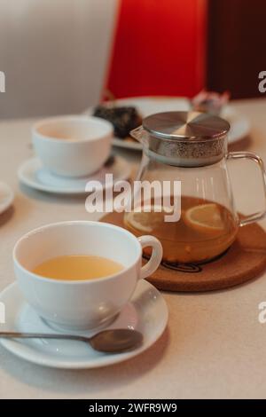 Tazza di ceramica bianca e teiera con tè all'arancia nella caffetteria Foto Stock