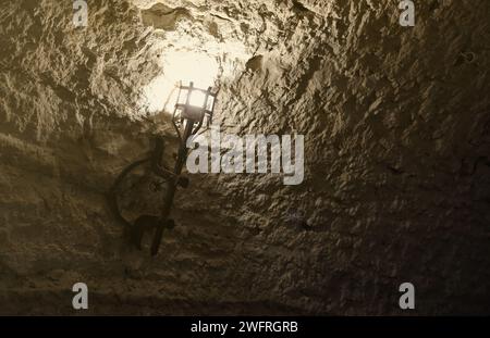 Torcia del castello medievale illuminata appesa a un muro di pietra, oggetti d'epoca e sfondo Foto Stock