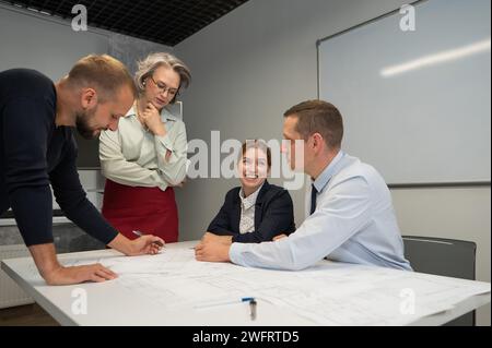 L'estrusione femminile valuta il lavoro dei subordinati. Progettisti ingegneri a una riunione. Foto Stock