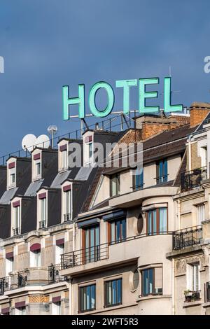 Cartello con la parola "HOTEL" scritta in lettere maiuscole luminose sulla sommità di un edificio a Parigi, in Francia Foto Stock