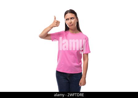 giovane donna europea ben curata con capelli lisci neri vestita con jeans tiene il pollice in alto Foto Stock